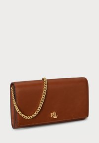 Brūns ādas maks ar zelta ķēdes siksnu, taisnstūra formā, ar zelta logo akcentu un gludu tekstūru.