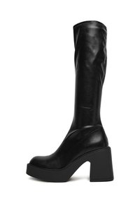 Cizme negre până la genunchi din piele netedă. Au un toc masiv și un vârf rotunjit, cu un brâu ajustat și detalii de coasere minime.