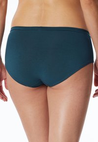 Boxer in cotone verde acqua con texture liscia, copertura media e design della vita, visti da dietro, che mettono in evidenza cuciture minime.