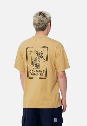 Camiseta de algodón en amarillo claro con mangas cortas. Presenta un gráfico negro de un personaje y la frase "CONTENIDO EN MILAGROS" en la parte de atrás.
