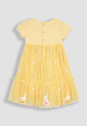 Sárga ruha csíkos felső résszel, rövid ujjakkal és réteges tüll szoknyával. Hímzett virágokkal, kacsákkal és nyúl motívummal díszített.