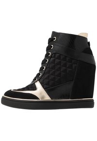 Svarta kilgymnastikskor med quiltade paneler, en texturerad svart överdel, metalliska accenter och en slät svart sula. Snören och en vadderad krage ingår.