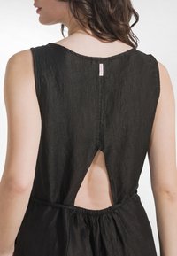 Vestido negro sin mangas con cuello alto, tela de lino texturizada, corte en la espalda y cintura elástica. Etiqueta visible en el cuello.