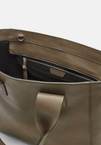 Skórzana torba typu tote w stonowanym oliwkowym kolorze, z teksturowanym wykończeniem, otwartym szczytem i wewnętrzną kieszenią na zamek wyłożoną czarnym materiałem.