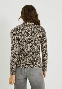 Haut à manches longues imprimé léopard beige et noir, fabriqué en tissu doux, avec une coupe ajustée, un col rond et des détails discrets de couture au dos.