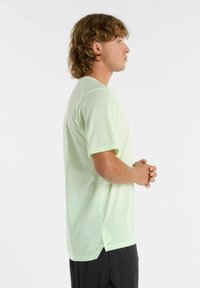 Vihreä, lyhythihainen urheilu-paidat tekstuuripinnalla, pyöreä pääntie, sivuviiltoja ja rento istuvuus. Yhdistetty mustiin shortsisiin.