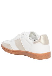 Baskets blanches avec un dessus en daim texturé et cuir, des accents dorés métalliques, et une semelle en caoutchouc avec un grip à motifs.