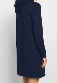 Marineblauwe sweatshirt jurk met capuchon, lange mouwen, zijzakken en rechte snit, gemaakt van een zachte, textuurstof.