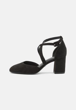 Black suede high-heeled shoe with a pointed toe, an open side, and crisscross ankle straps. Block heel provides stability.
