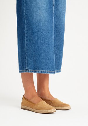 Scarpe slip-on in suede marrone chiaro con suola in corda di juta, abbinate a pantaloni culottes in denim di un blu medio.
