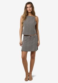 Fekete-fehér mintázatú szett, amely egy rövidített, ujj nélküli felsőből és egy gomb részlettel és derékpánttal ellátott, hozzáillő szoknyából áll.