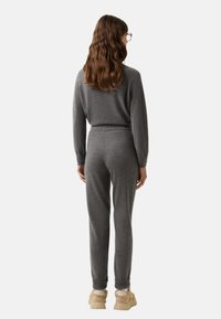 Grau gestricktes Loungewear-Set mit lockerer Passform. Der Pullover hat gerippte Bündchen; die Hose hat einen elastischen Bund und tapered Knöchel.