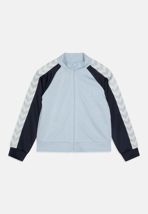 Lichtblauwe zip-up jas met marineblauwe mouwen en een gemêleerd chevronpatroon op de schouders. Voorzien van een staande kraag en elastische manchetten.