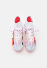 Scarpe da ginnastica bianche con un motivo a gradiente arcobaleno, caratterizzate da una vestibilità aderente e un interno rosso brillante. I lacci sono bianchi con accenti rossi.