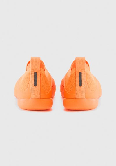 Ζευγάρι φωτεινά πορτοκαλί slip-on αθλητικά παπούτσια που έχουν γυρισμένη την πλάτη τους με μία μαύρη κάθετη λωρίδα στις πίσω γλωττίδες, πάνω σε ανοιχτό γκρι φόντο.