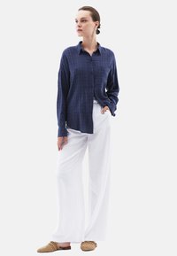 Marinblå rutigt skjorta med knappar, avslappnad passform, matchad med vita vida byxor och ljusbruna vävda slip-on skor.