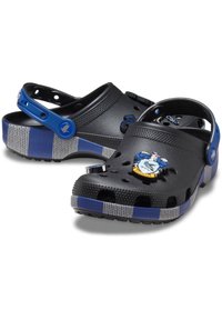 Black rubber clogs with blue strap, featuring holes for ventilation. Gray and blue striped sole. Ravenclaw emblem detail on the front.