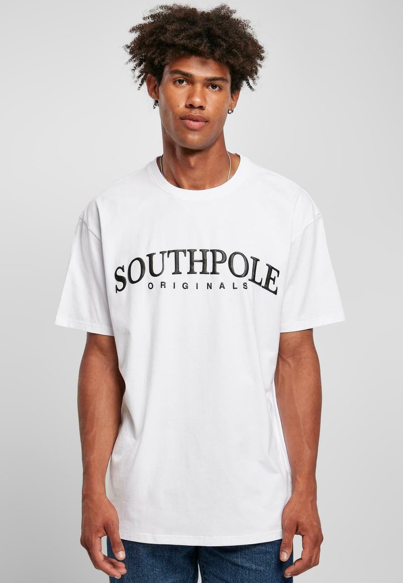 Camiseta de algodón blanca con un logo gráfico negro "SOUTHPole ORIGINALS" en el pecho, de manga corta y corte relajado.