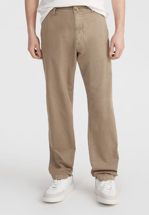 Beige cotton trousers with a relaxed fit, featuring a button closure, front pockets, and elastic cuffs. Paired with white sneakers.