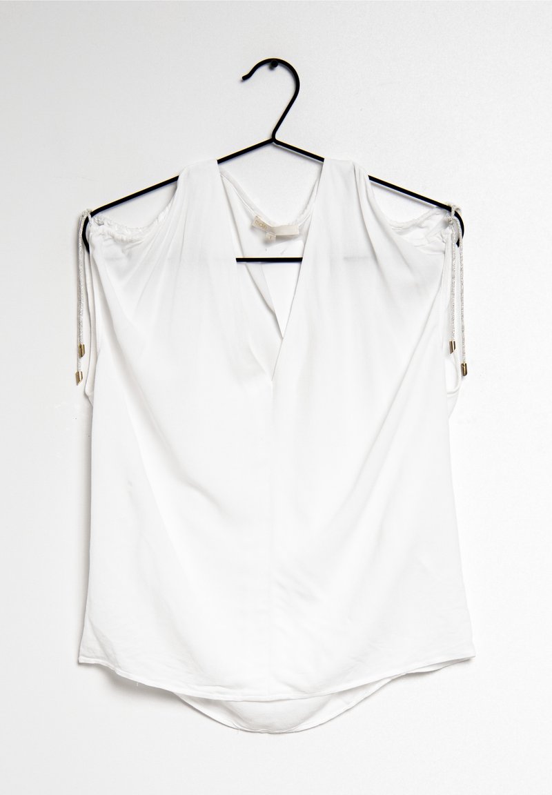 White, short-sleeved blouse with a deep V-neck and rounded hem, made from smooth fabric. Features drawstring accents at the shoulders.