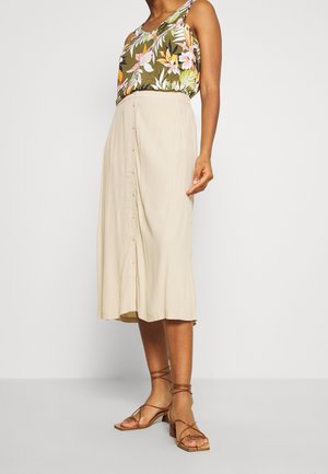 Débardeur à imprimé floral en vert, jupe midi à boutons beiges, sandales à lanières beiges. Tissu doux, coupe décontractée, longueur cheville, brillance subtile.