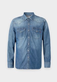 Camicia di denim in azzurro chiaro, con colletto a punta, maniche lunghe, due tasche sul petto con bottoni a pressione e una texture leggermente strappata.