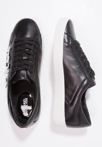 Black leather sneakers with a smooth texture, featuring a white rubber sole, round toe, lace-up front, and silver hardware accents.