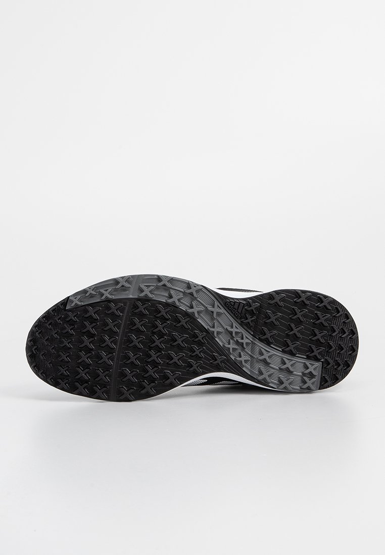 Semelle de chaussure de sport noire en caoutchouc texturé, avec une semelle intermédiaire grise et des accents blancs sur les côtés.