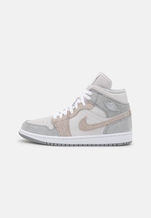 Basket montante avec lacets blancs, panneaux en suède gris clair et beige, logo Nike swoosh et logo Air Jordan sur le col de la cheville.