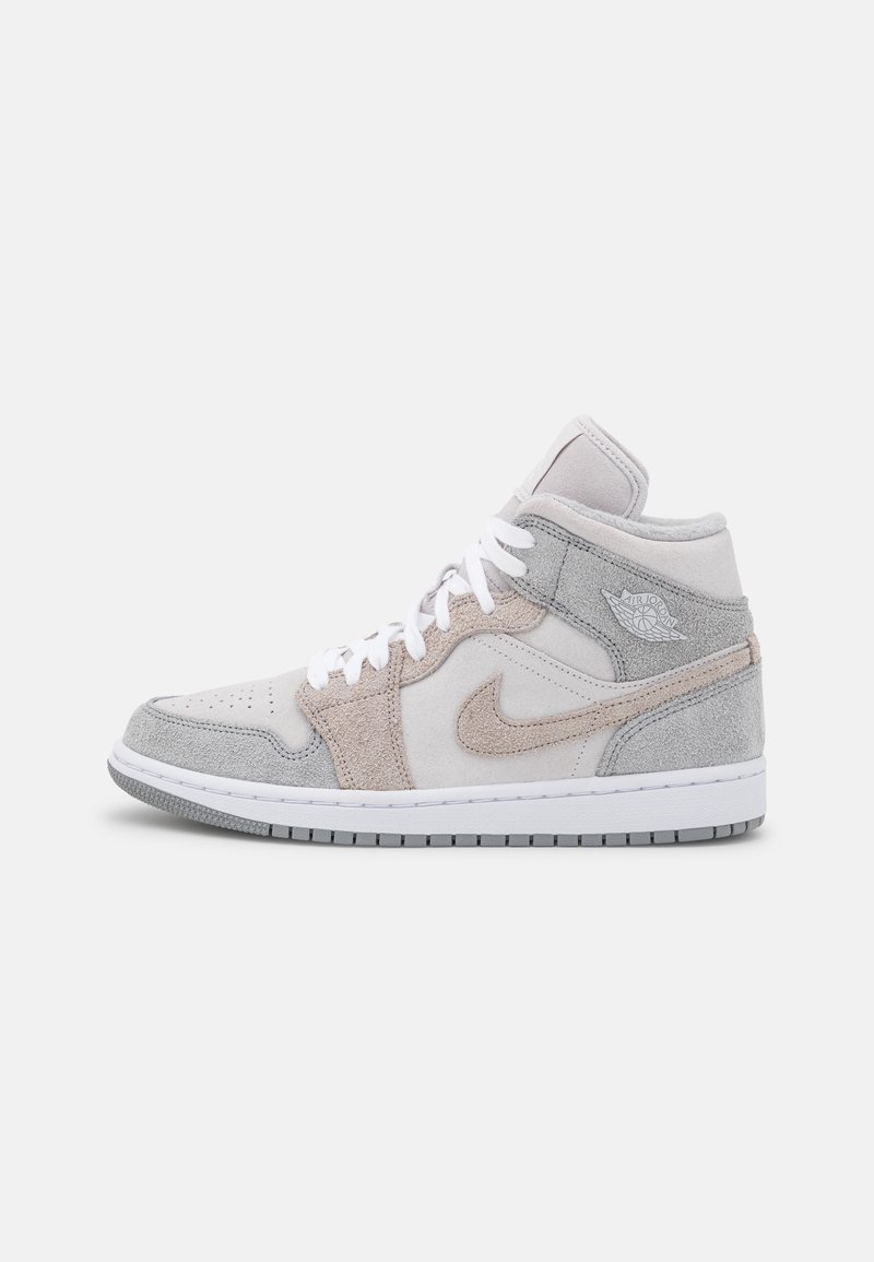 Basket montante avec lacets blancs, panneaux en suède gris clair et beige, logo Nike swoosh et logo Air Jordan sur le col de la cheville.