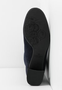 Granatowe zamszowe buty na gumowej podeszwie. Teksturowana podeszwa ma tłoczone wzory, w tym nazwę marki "Peter Kaiser."