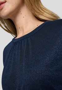 Navyblaues, metallisches Stoffoberteil mit weicher Textur, rundem Ausschnitt und subtilen Raffungdetails an den Schultern.