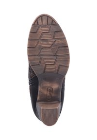 Chaussure en cuir noir avec une semelle en caoutchouc brun texturé. La semelle présente un motif de semelle hexagonal pour une meilleure adhérence. Détail de fermeture éclair sur le côté.
