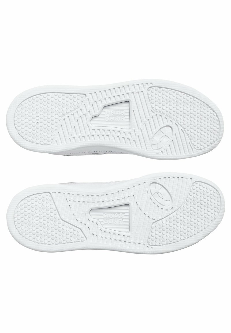 Suela de zapatillas deportivas blancas con una superficie de goma texturizada, un agarre con patrón, un logotipo central y una zona de talón reforzada.