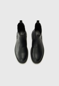Botas de tobillo negras hechas de cuero texturizado con un acabado suave, que cuentan con paneles laterales elásticos y una lengüeta para ponerlas y quitarlas fácilmente.