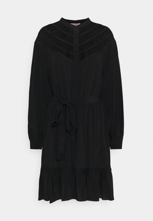 Černé dlouhé šaty s dlouhým rukávem a vysokým límcem, s plisovanými detaily na ramenou, s tkaným páskem a volánkovým lemem. Hladká textilie.