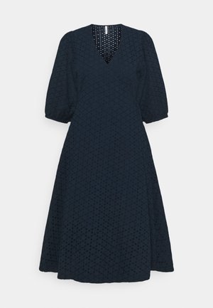Robe midi noire avec col en V et manches trois-quarts bouffantes, présentant un motif texturé à pois et une silhouette évasée en A.