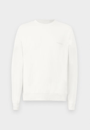 Hvit crewneck genser laget av mykt stoff, med ribbestrikkede mansjetter og nederkant, med en subtil logo trykket på brystet i lys grå.