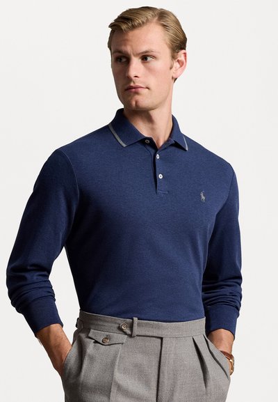 Navy langærmet polo shirt i blødt stof, med en kontrasterende grå krave og tre-knaps lukning, parret med lysegrå bukser.