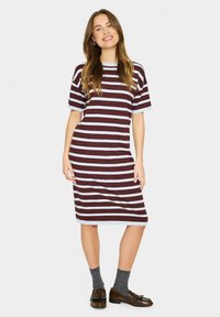 Rochie stripedă în nuanțe de burgundy și albastru deschis, realizată dintr-un material moale. Are mâneci scurte și o lungime până la genunchi. Este asortată cu șosete închise la culoare și pantofi.