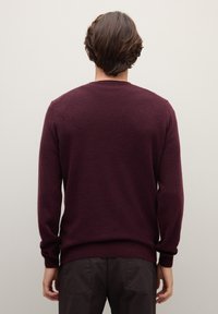 Maglione bordeaux in morbido materiale a maglia, con maniche lunghe, polsini e orlo a coste, e classico scollo rotondo.