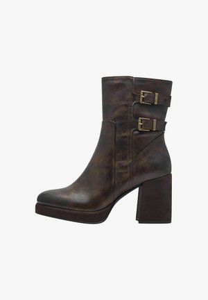 Bottines en cuir marron avec deux accents de boucle, un bout rond et un talon épais. Fini texturé avec une surface lisse.