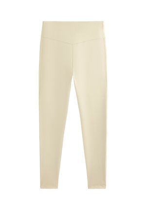 Beżowe legginsy z wysokim stanem i ozdobnym szwem w kształcie litery V w talii, prezentowane na białym tle.