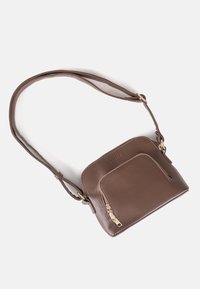 Bolso cruzado de piel marrón con correa ajustable, bolsillo frontal con cremallera y detalles de cremallera en tono dorado sobre fondo blanco.