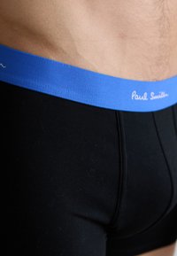 Sorte boxershorts med en blød, glat tekstur og en lyseblå elastisk livrem med "Paul Smith" i hvid brodering.