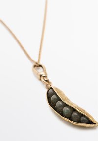 Náhrdelník se zlatým přívěskem ve tvaru lusku, uvnitř se nachází pět tmavozelených korálků, zavěšený na tenkém řetízku.