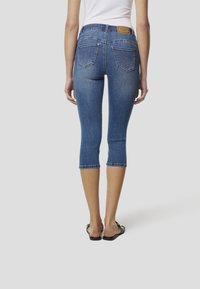 Zilas džinsa īssarīkas ar pieguļošu dizainu, vidēji augstu vidukli un divām aizmugurējām kabatām ar dekoratīvu šuvumu.