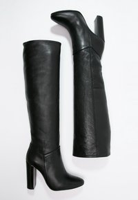 Schwarze Lederstiefel bis zum Knie mit einer spitzen Zehe und einem klobigen hohen Absatz. Die Oberfläche hat eine glatte Textur und ein figurbetontes Design.