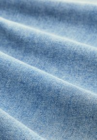 Világoskék farmeranyag sima felülettel, finom szőtt mintákkal és enyhe árnyalateltérésekkel a felületen.