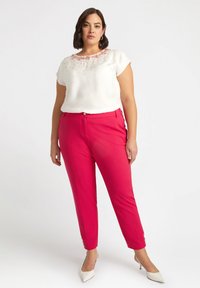 Top bianco a maniche corte con decorazioni rosa al colletto, abbinato a pantaloni tapered rosa brillante e décolleté bianchi.